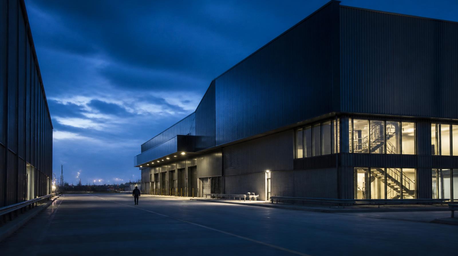 A large South African industrial facility at blue hour, with a lone figure for scale.